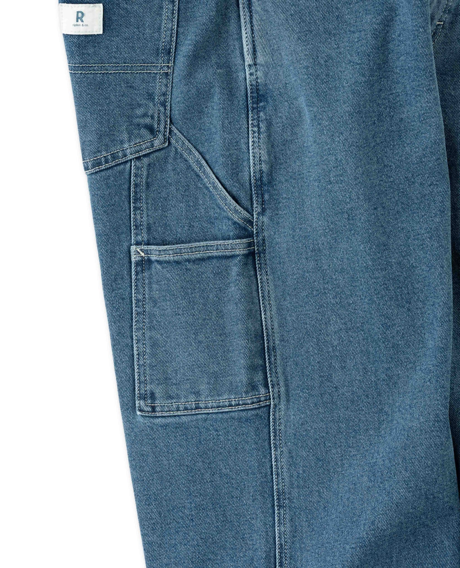 Close-up of blue denim pants with a brand label on a white background
