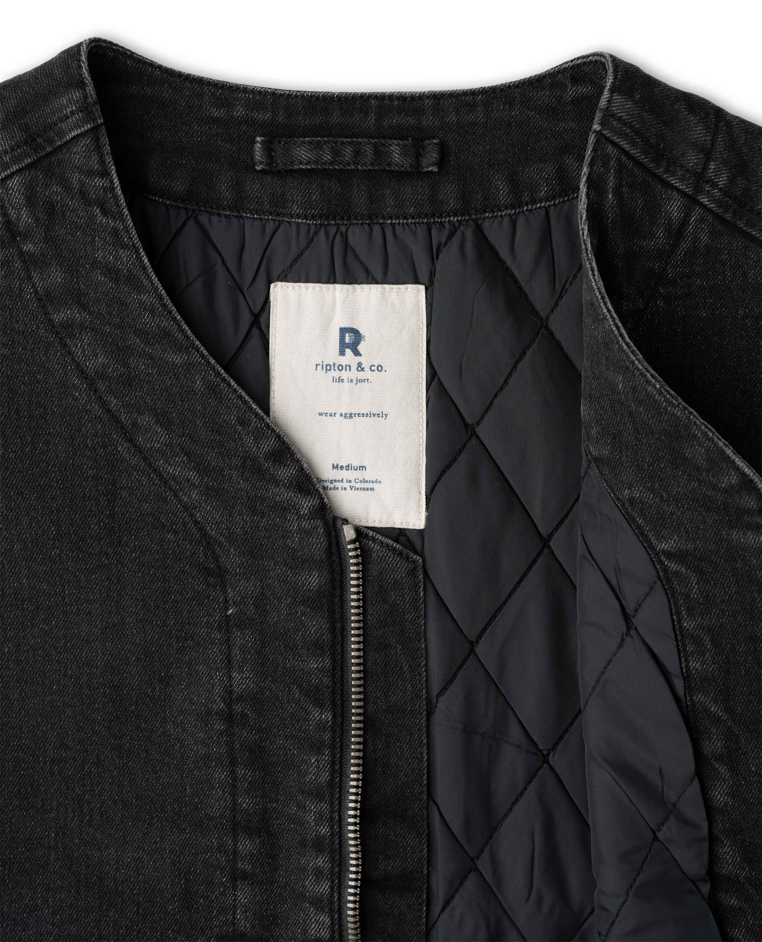 Close-up of a black zip-front jacket with a quilted black lining and a visible white neck label.