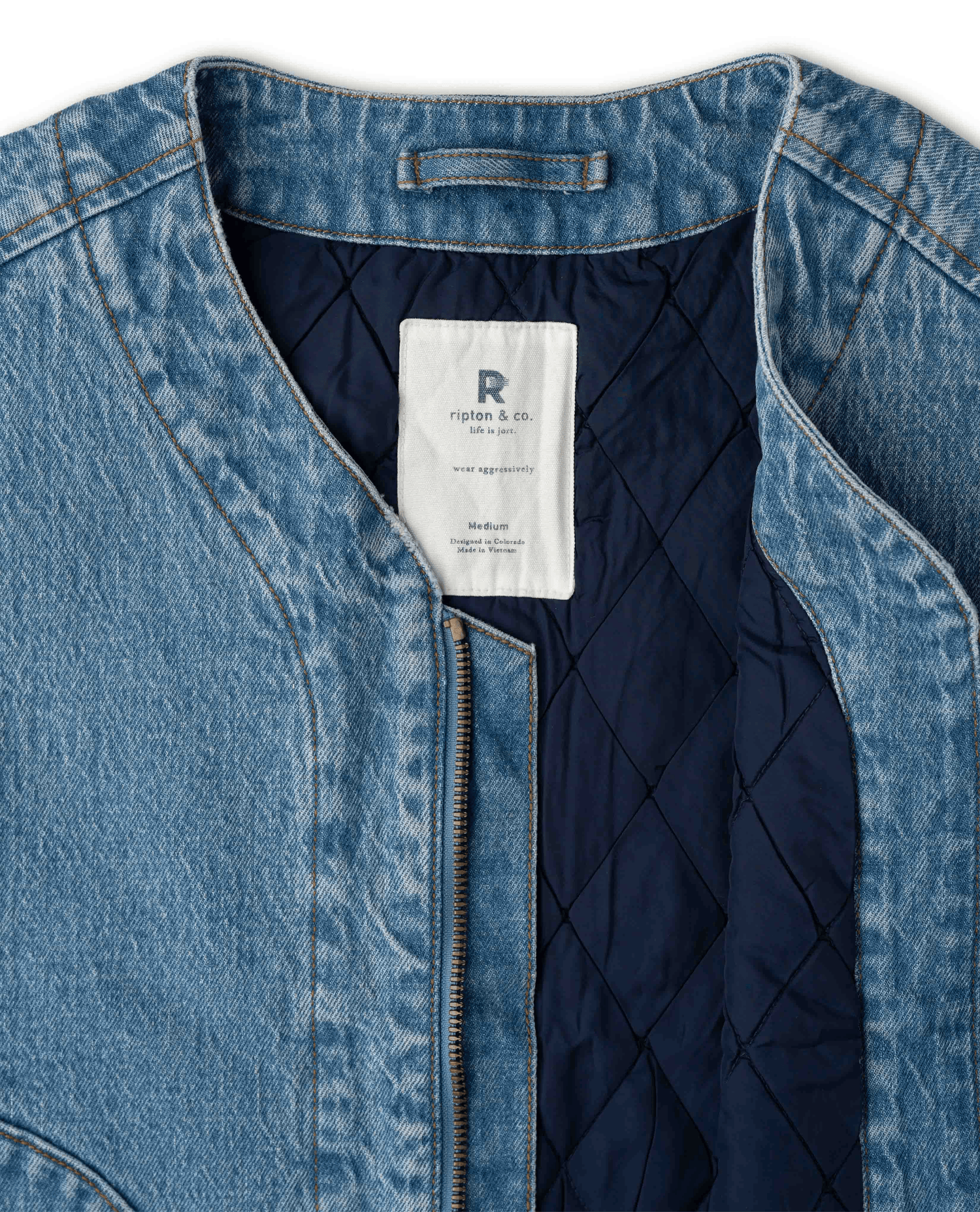Close-up of a denim jacket with a dark navy quilted lining and a white interior label.