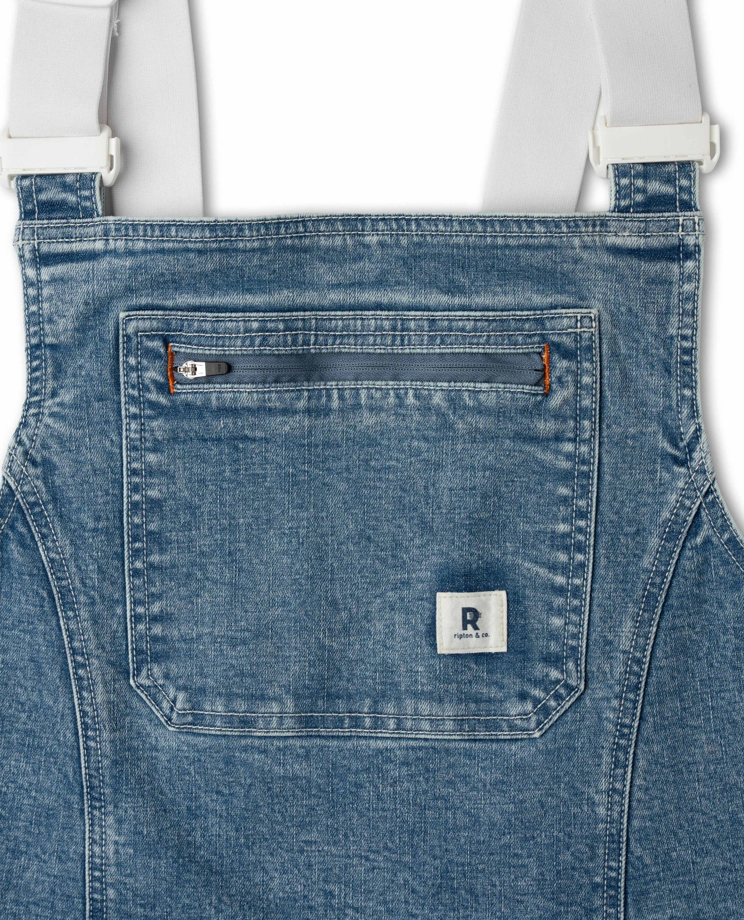 Close-up of blue denim overalls with a visible brand logo on the pocket.