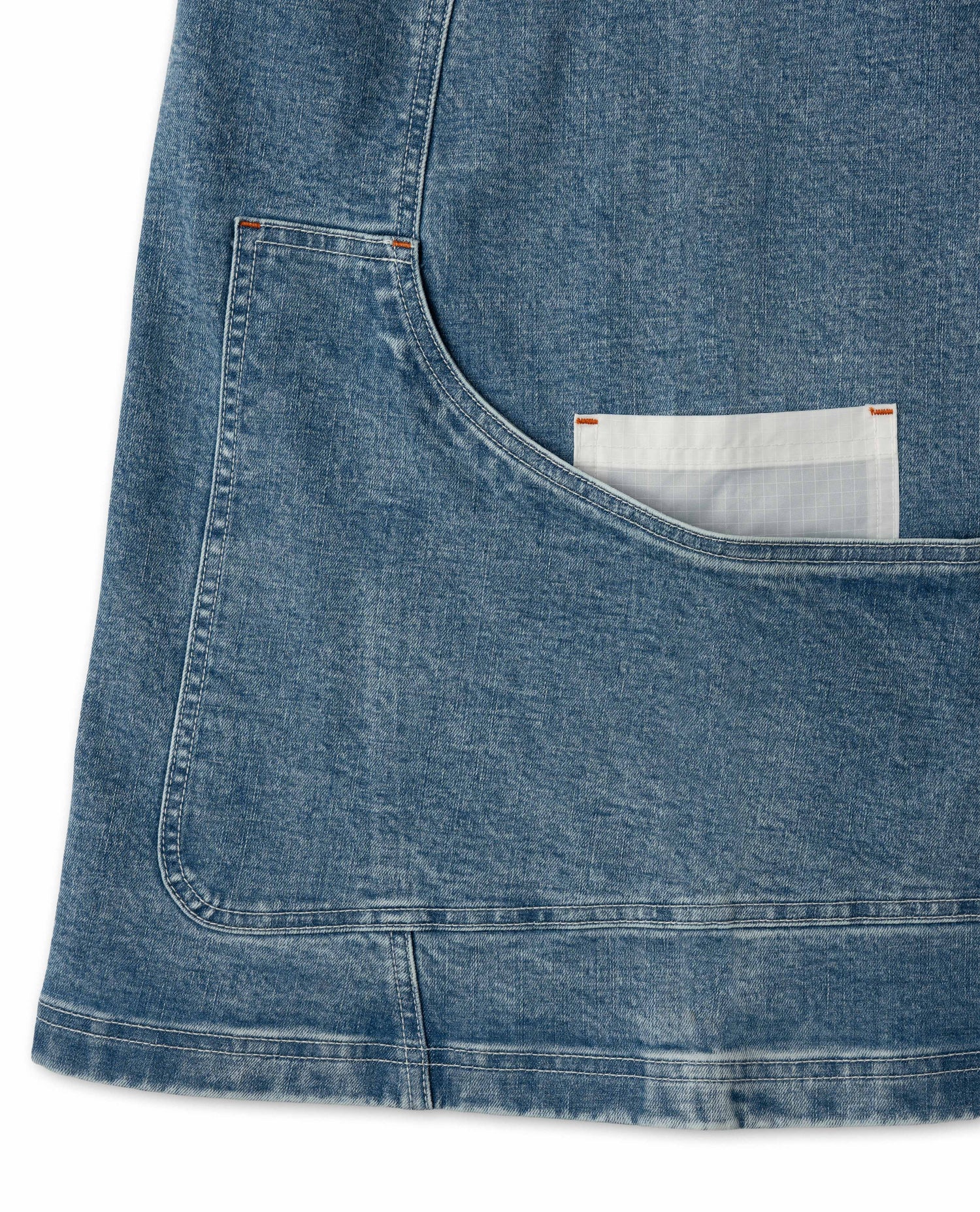 Close-up of a blue denim pocket with a white label on a white background