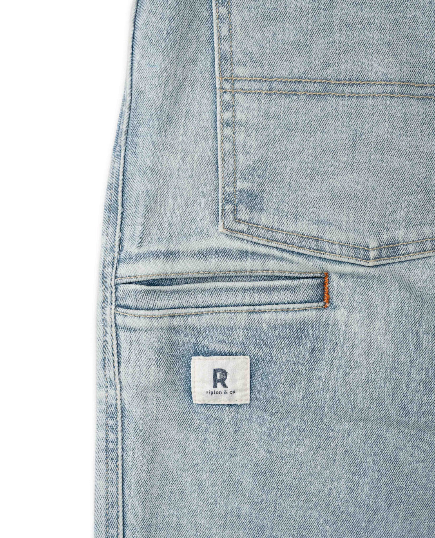 Close-up of a light blue denim pocket with a brand label on a white background