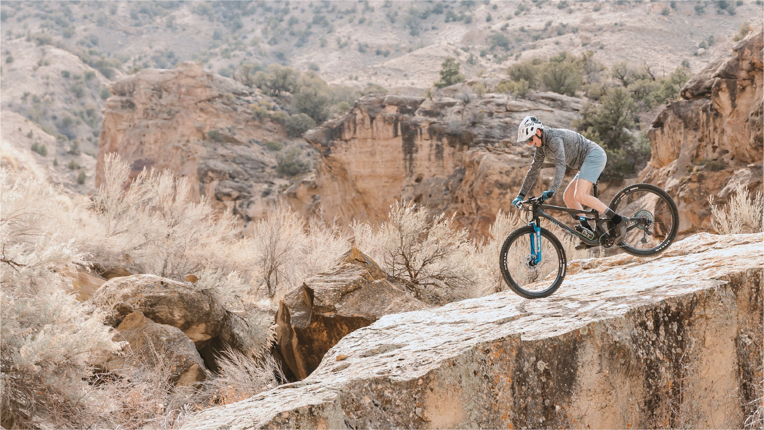 A man in activewear riding a mountain bike over a rocky surface.