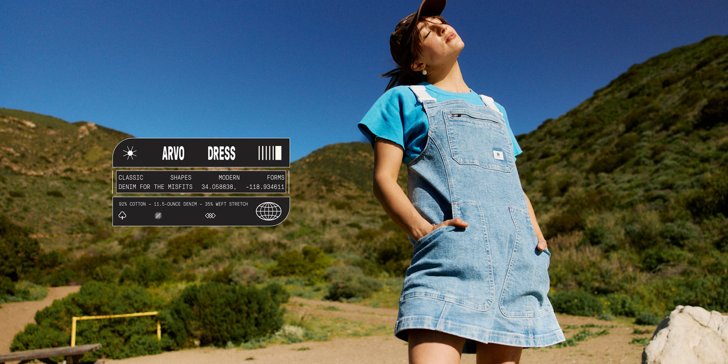 Person wearing a denim dress standing outdoors with a scenic background