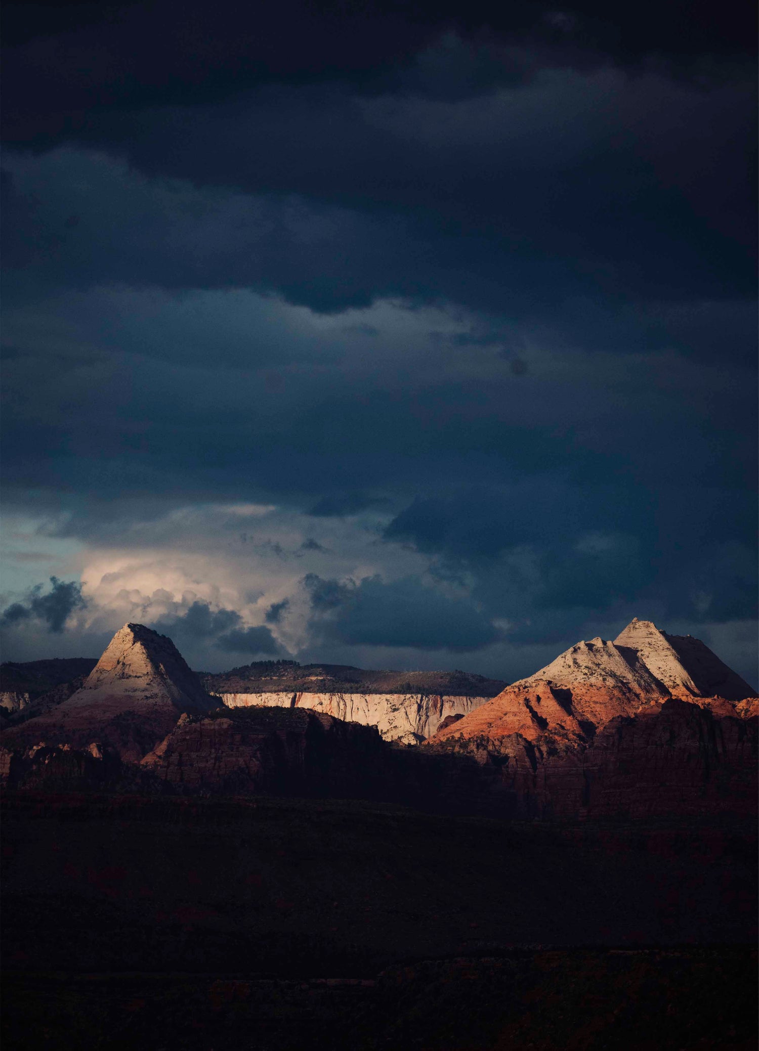 Sunlight breaking through dark clouds over a mountain landscape