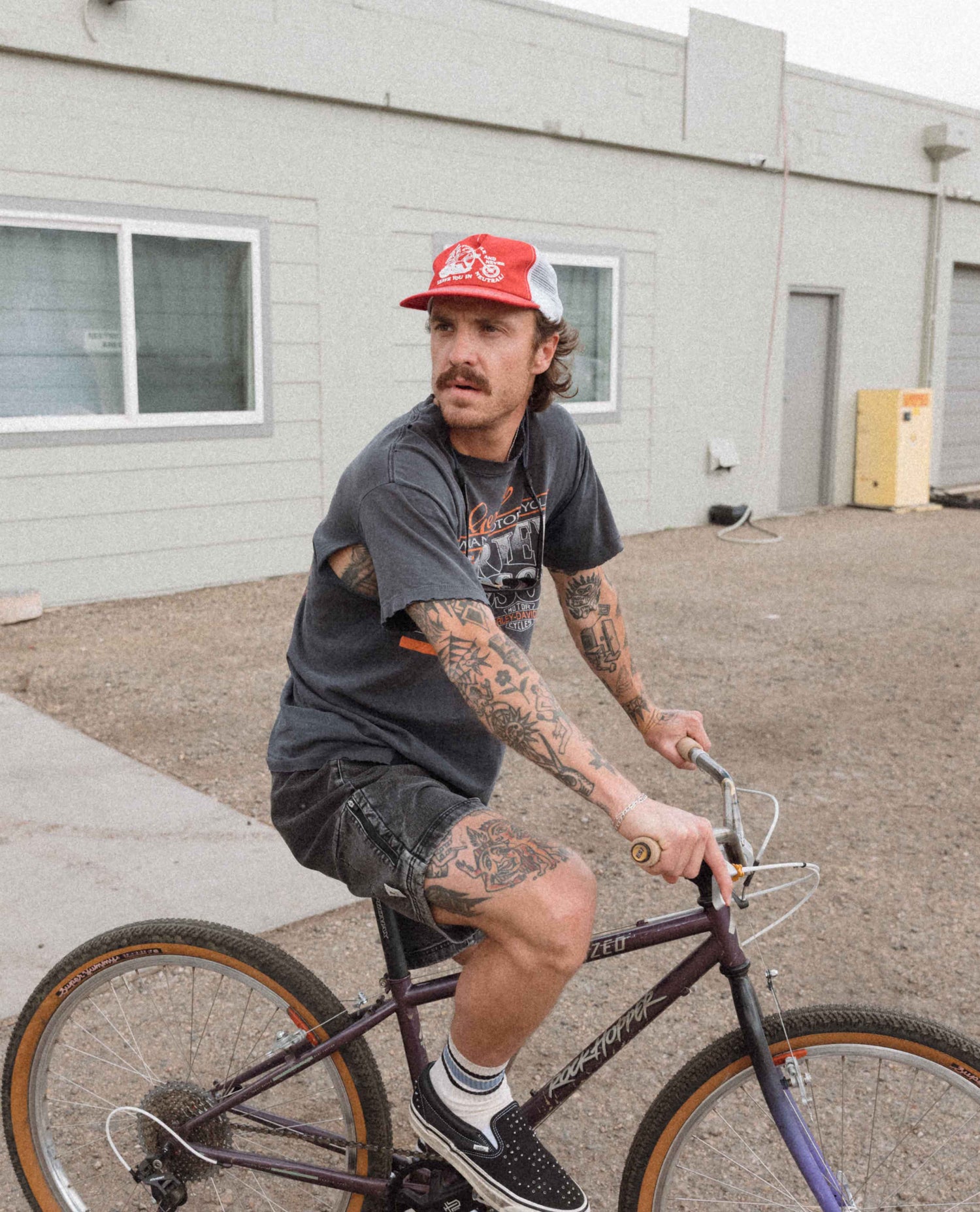 Man with tattoos riding a bicycle in an urban setting