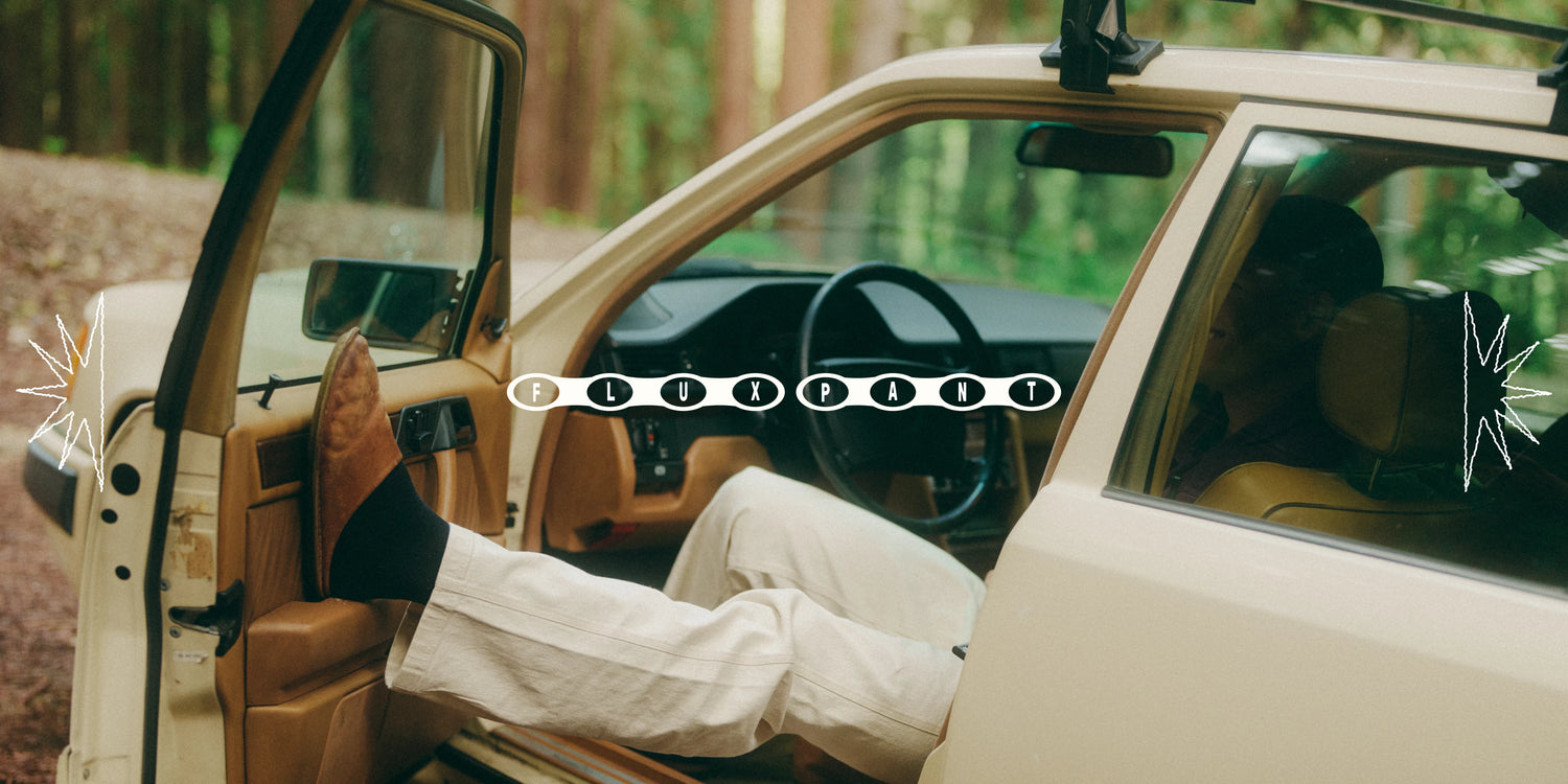 Person's feet in brown boots and white pants stepping out of a beige car with Flux Pant branding.