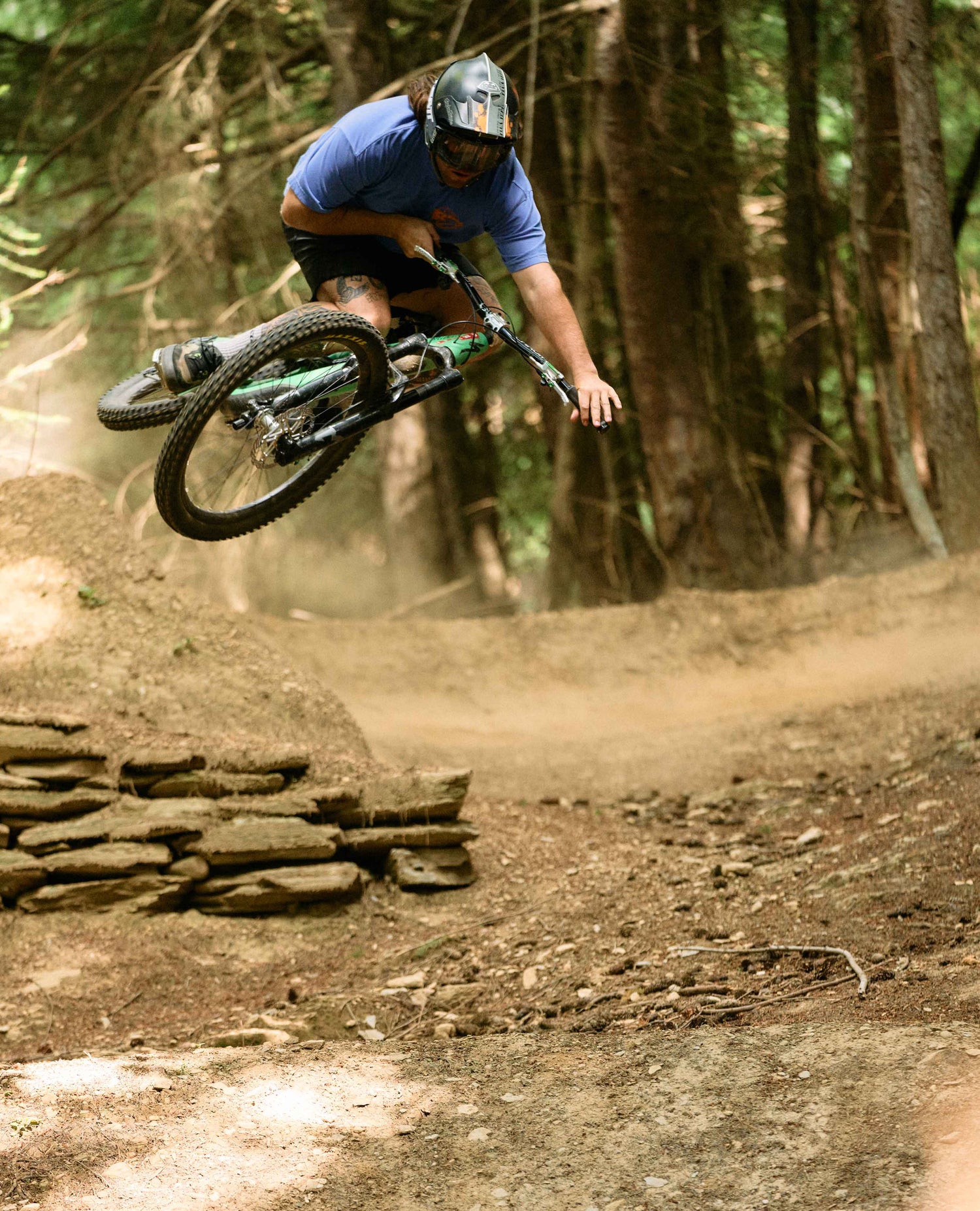 Person riding a mountain bike on a dirt trail with trees in the background