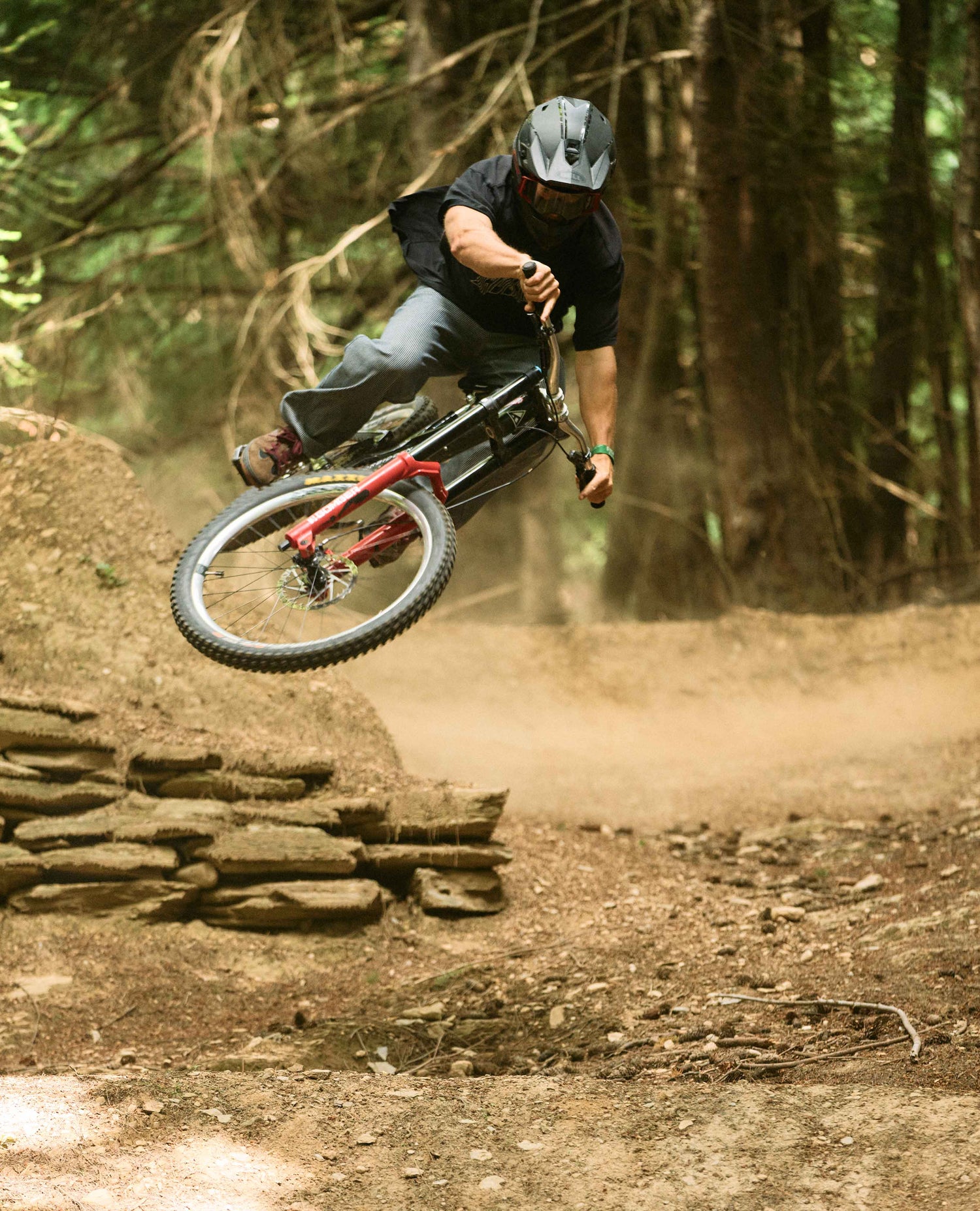 Person riding a mountain bike on a dirt trail with trees in the background