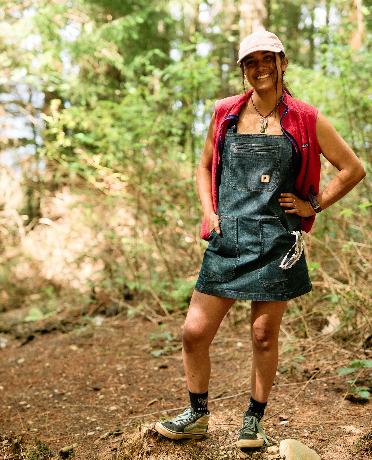 Person wearing a denim apron and red shirt in a forest setting
