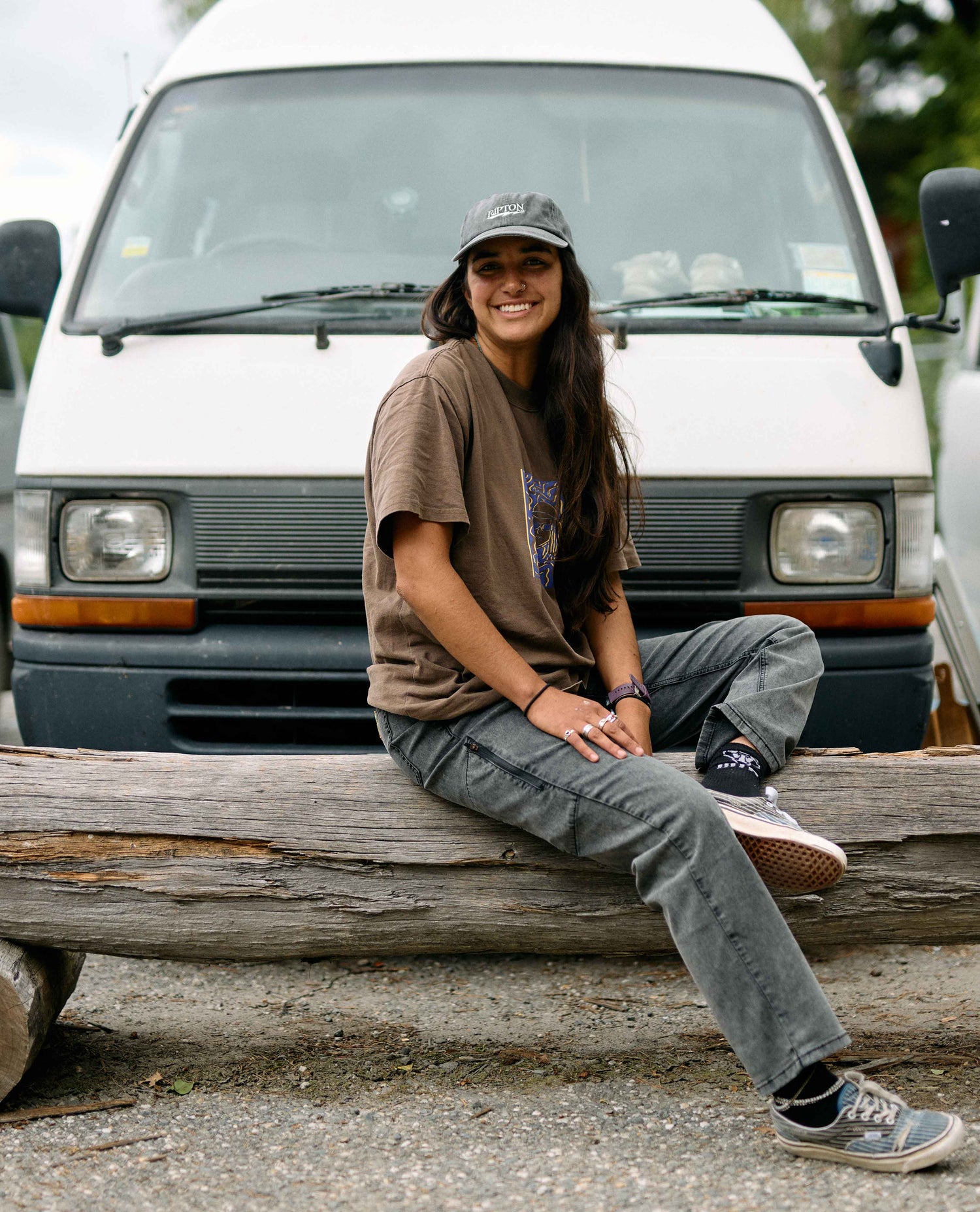 Person sitting on a log in front of a white van